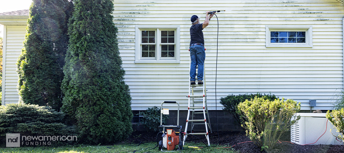 Someone pressure washing the side of a house.