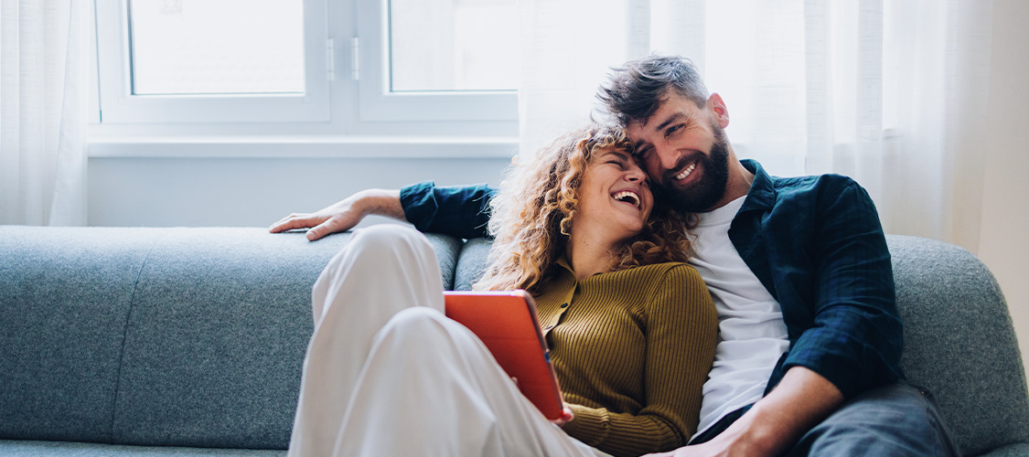 A man and a woman cuddling on the couch.