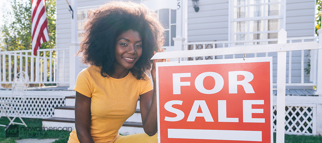A woman in front of a For Sale sign. 