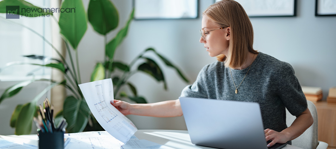 A woman sitting at a desk looking at paperwork.