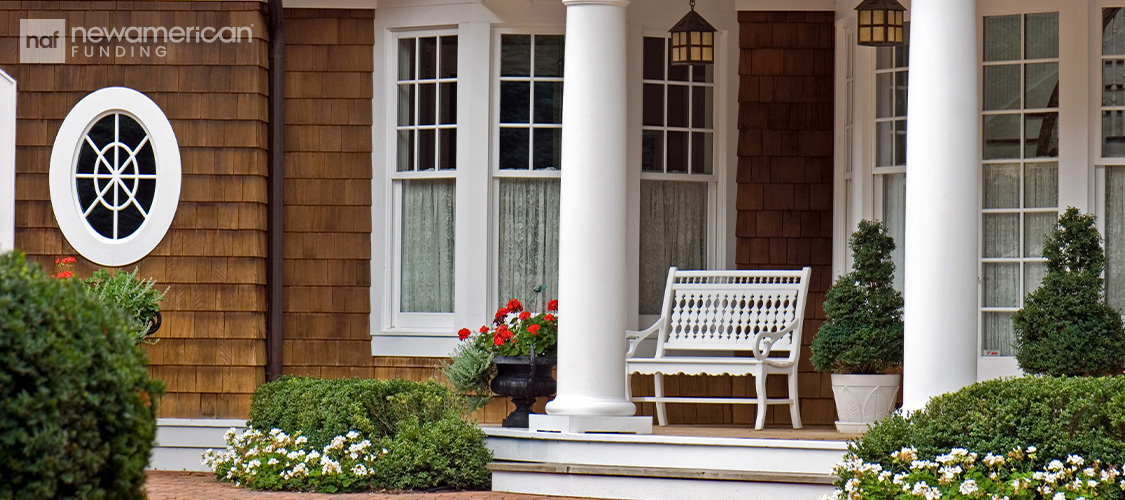A charming front porch with plants and a bench.