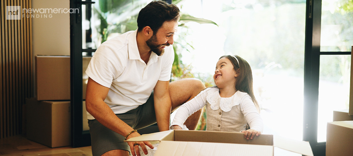 A father talking to a young girl as they pack a box.