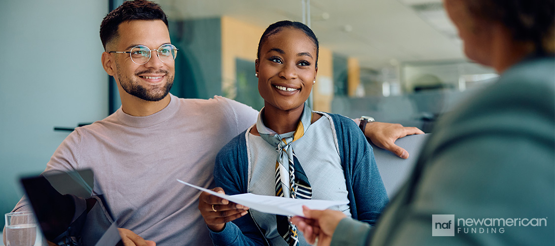 A couple sitting across from a loan officer in an office.