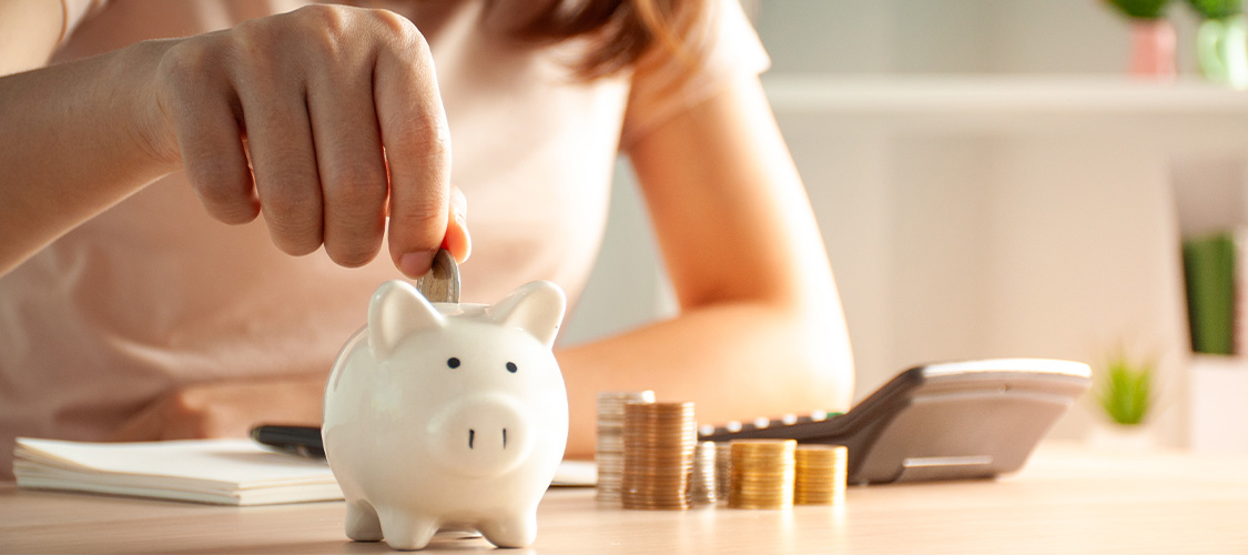 A person putting coins into a piggy bank