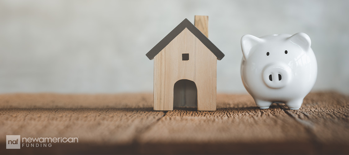 A block in the shape of a house next to a piggy bank.