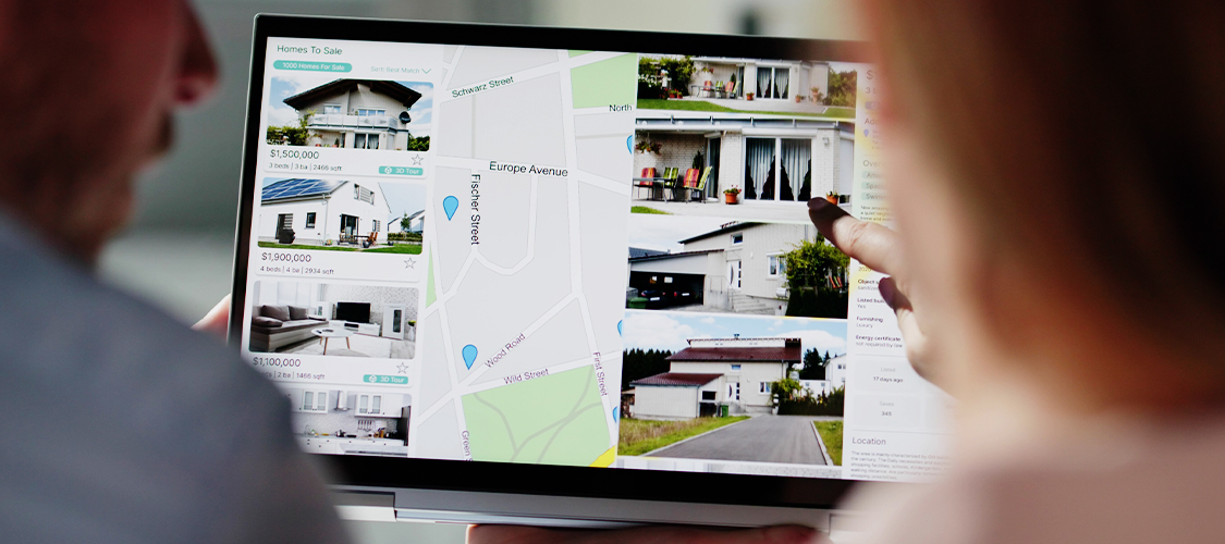 A couple browsing home listings on a laptop.