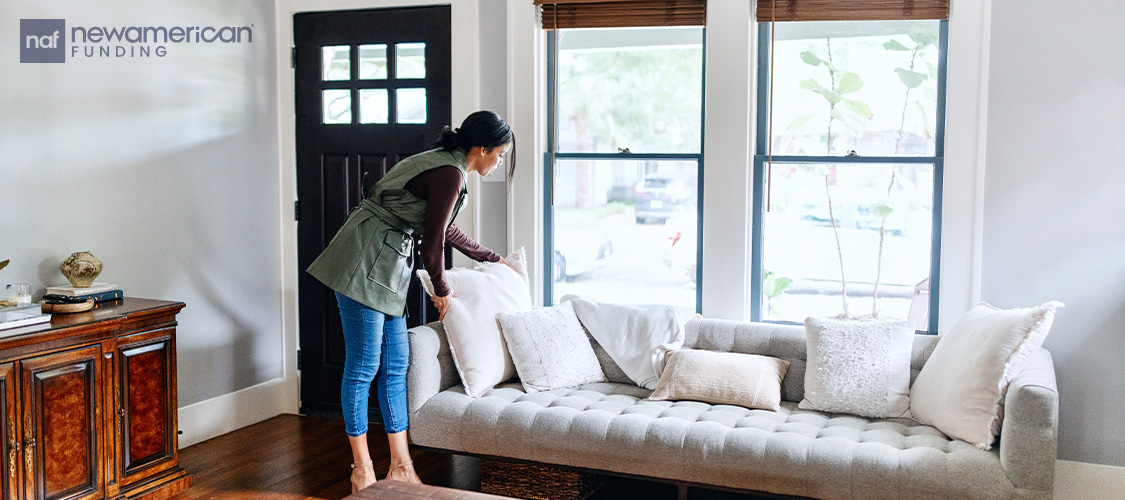 Someone staging a home, fluffing pillows on a couch.