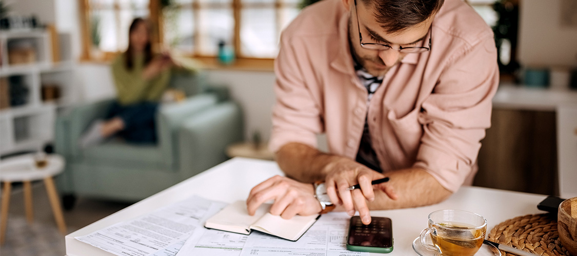 A man sitting down at a table making notes.