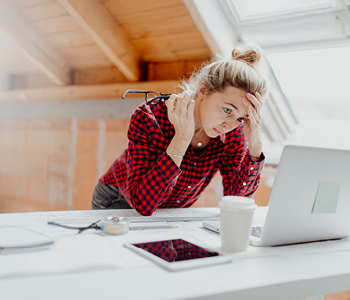 Mlada svetlolasa ženska med delom sloni na mizi in poskuša dvigniti koncentracijo
