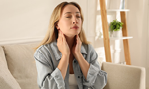 Mlada ženska tipa svoje bezgavke. Simbolna fotografija za pomen rednih pregledov pri zdravniku.