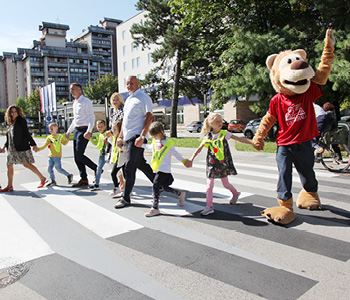 Skupina otrok s predstavniki zavarovalnice Generali in Generalijevo maskoto na 3D zebri.