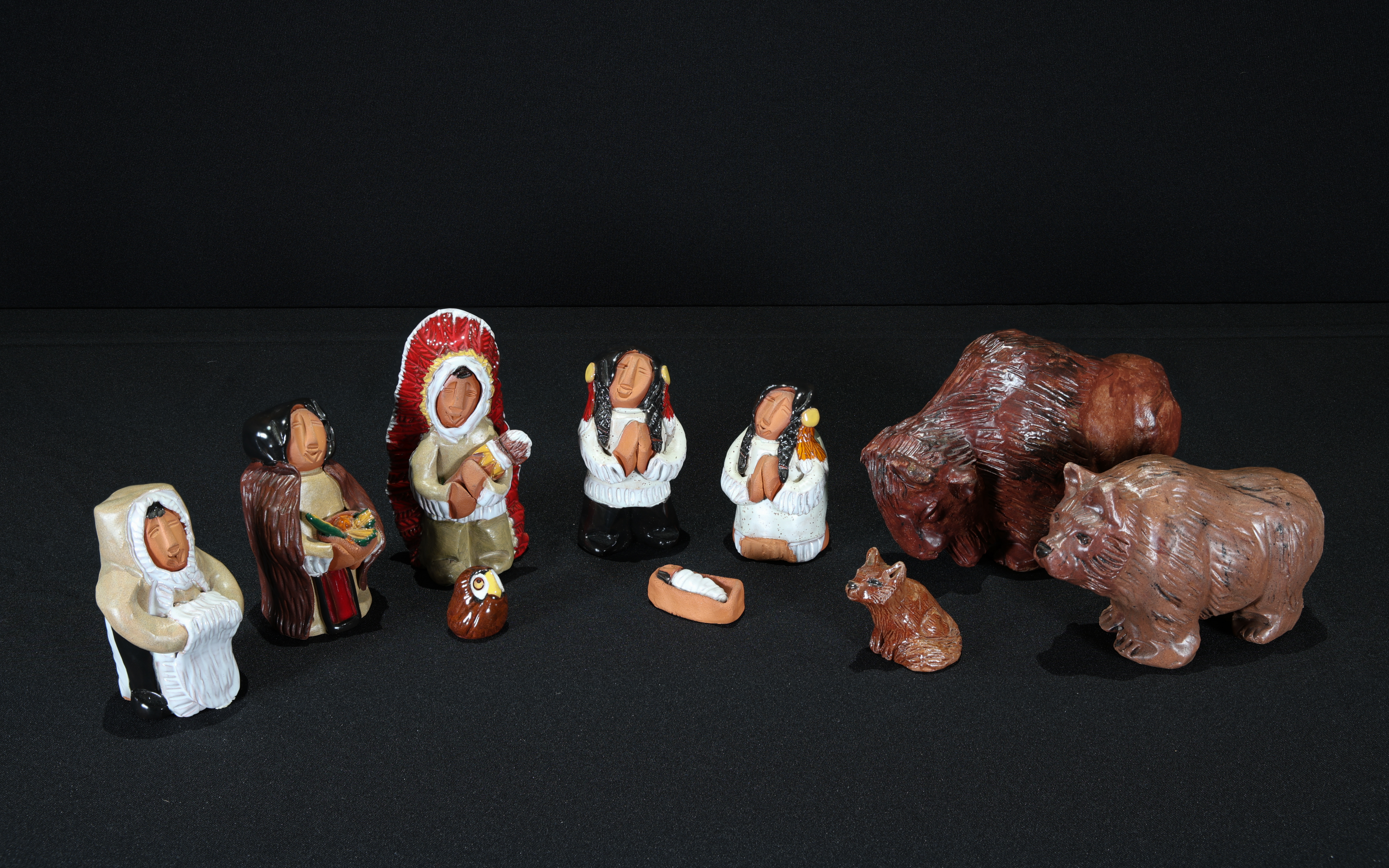 Painted clay Nativity with Holy Family and 3 Magi dressed in indigenous clothing along with a wolf, a bear, an owl, and a bison. 