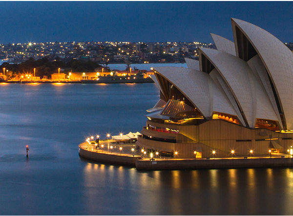 Sydney Opera House at night with city lights in the background