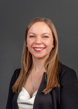 Headshot of Sarah Hochstatter, who smiles while wearing a cream blouse and black blazer suit