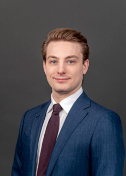 Headshot of Sean Phelan, who smiles while wearing a dark blue suit and a maroon tie