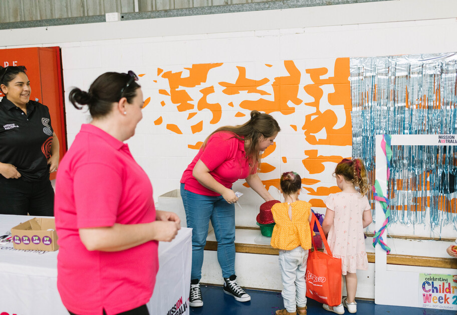 Service staff from Dubbo service Happy, Healthy Minds talk to two young toddlers at an event. 