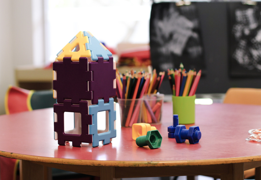 Stacking blocks arranged to form a small, colourful house on a table.
