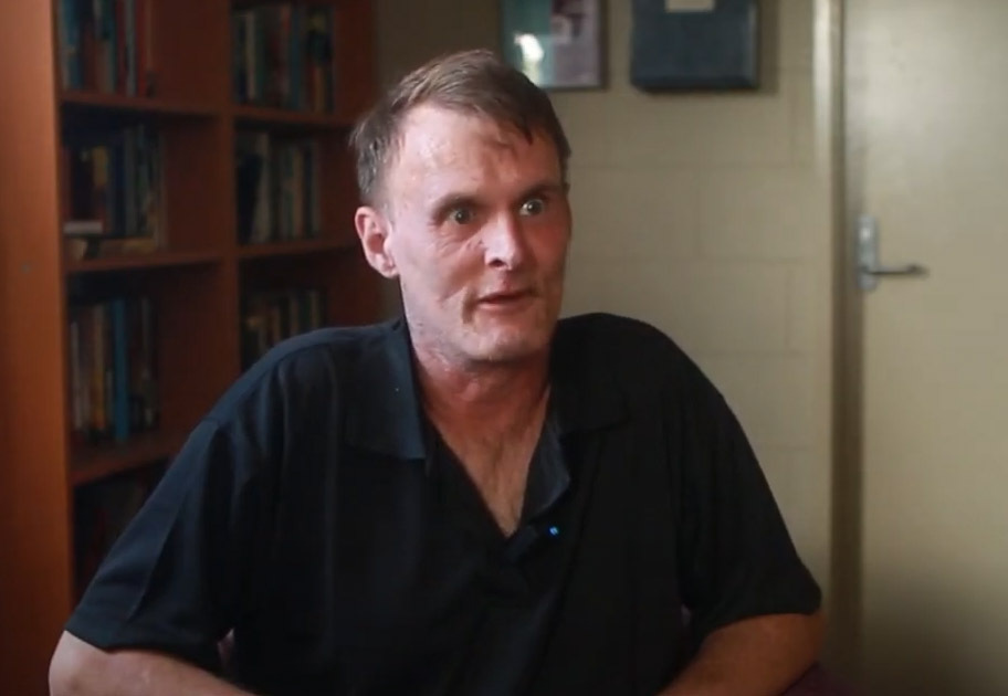 Ben sits in a chair while talking to camera about how Mission Australia helped him on his journey. 