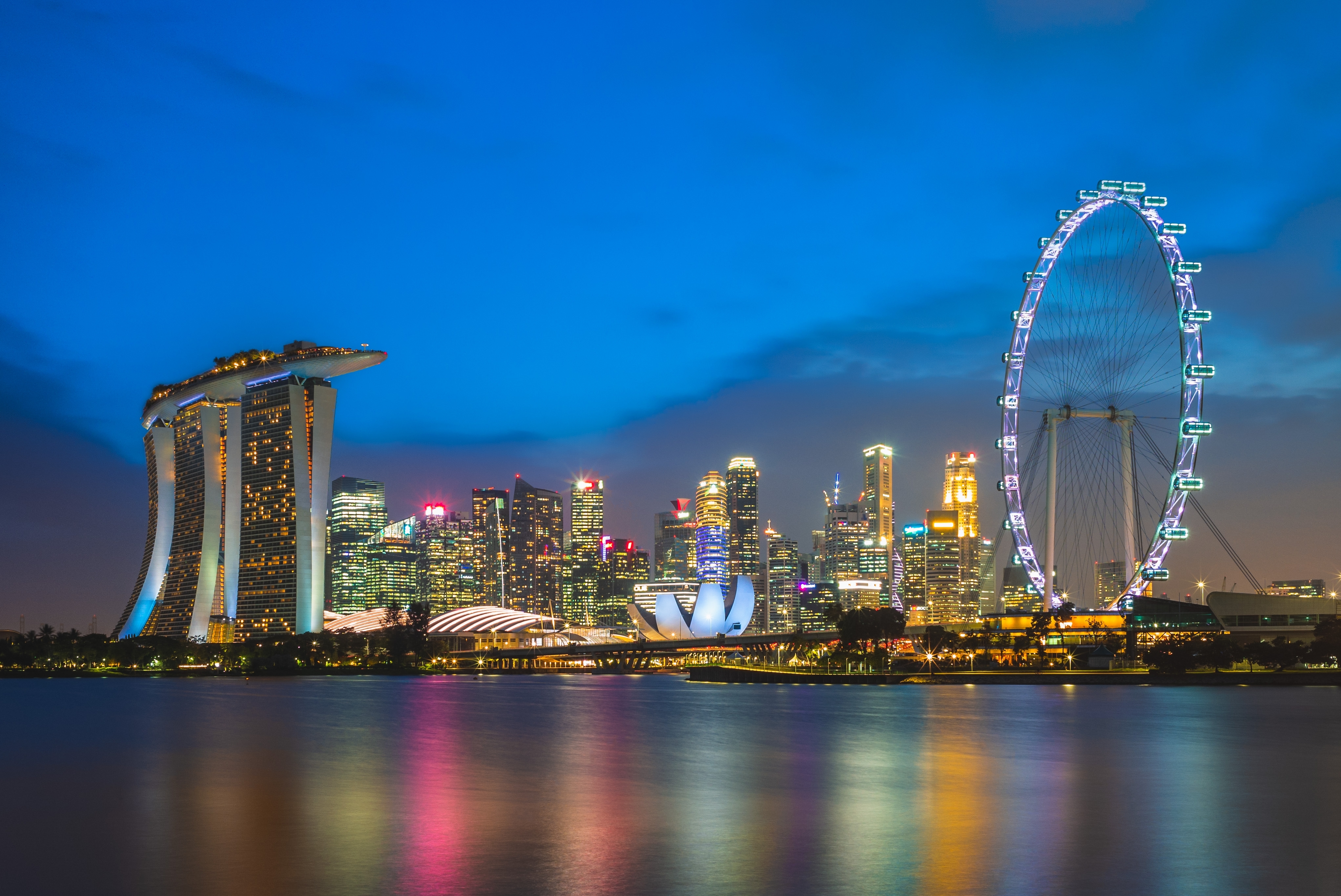 Skyline of singapore at marina bay and gardens- showing several skyscrapers and a giant ferris wheel