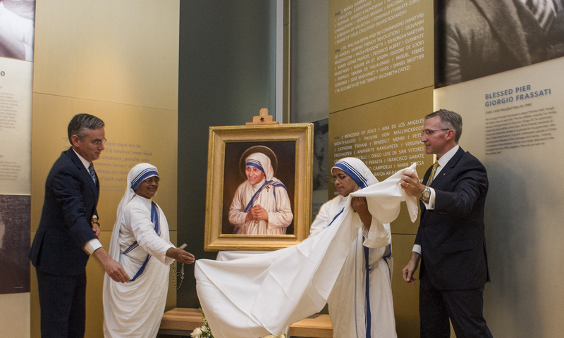 Supreme Knight Patrick Kelly and Thomas Hamling with sisters from the Missionaries of Charity in front of a portrait painting of St.Theresa