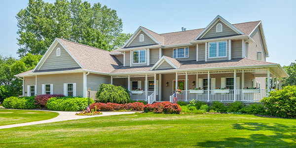 A nice two-story beige vinyl-paneled home sits in a well manicured lawn