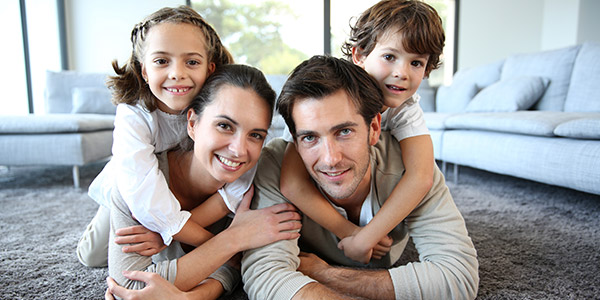 A happy white family plays in the living room of their home
