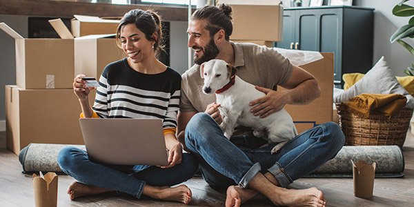 couple sitting on the floor of their new home with their dog