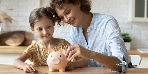 mother and daughter putting coins into a piggy bank