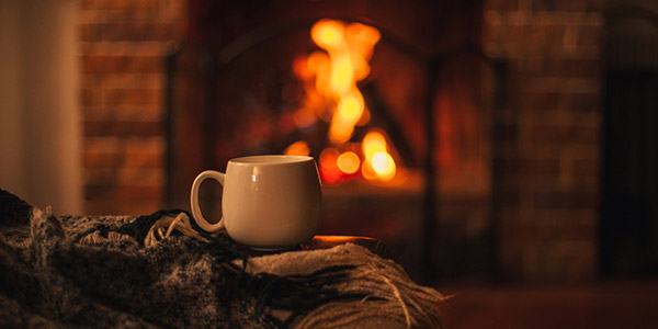 hot drink in front of the fireplace with a blanket