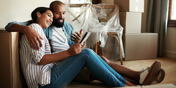 young homeowners sitting on the floor surrounded by moving boxes