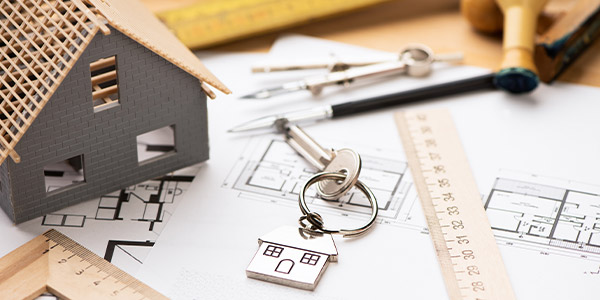 house keys sit on top of home construction plans