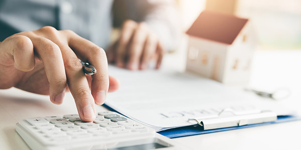 A person sits at a table using a calculator and pen and paper