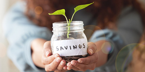 woman holding a saving jar with a plant growing from it