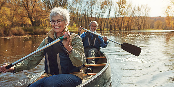 happy senior couple rowing a bow in the lake