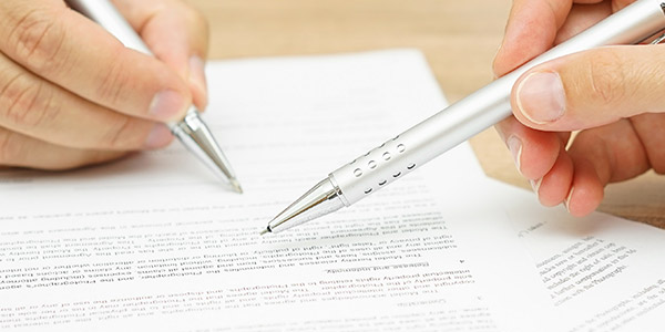 A photo of two hands signing paperwork 