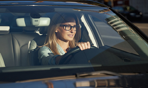 Mlada ženska z očali za volanom modernega avtomobila.