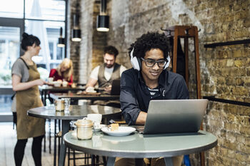man working on laptop at a coffee shop using the public wifi
