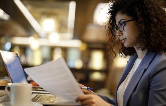 Business woman reading with laptop in cafe