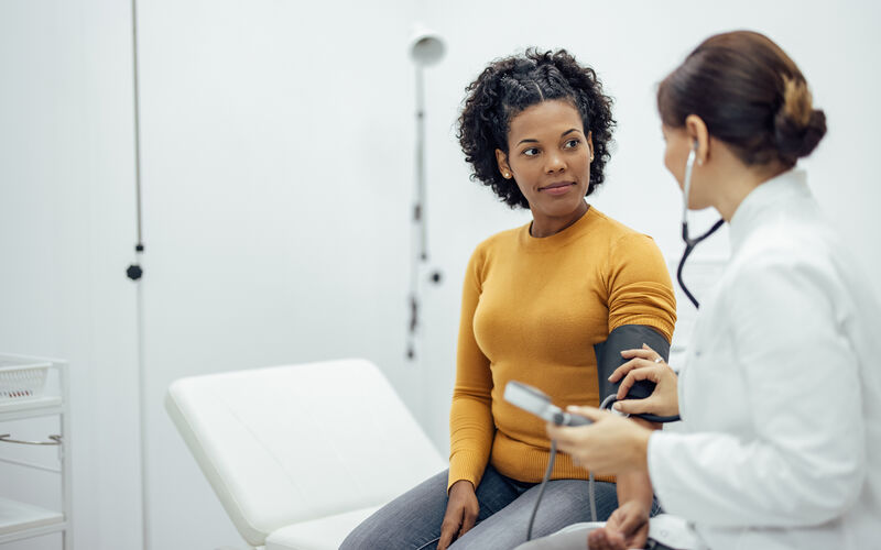 Doctor measuring blood pressure to a smiling woman