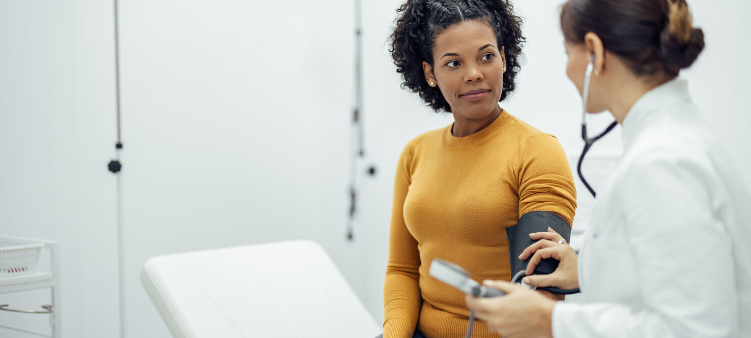 Doctor measuring blood pressure to a smiling woman