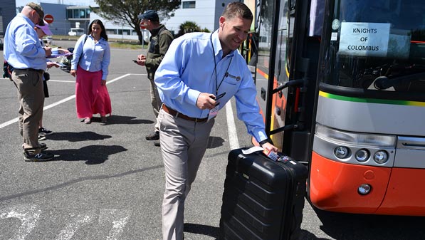 Knights of Columbus staff help onload luggage from bus for attending pilgrims.