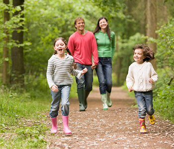 Družina na družinski dan uživa na sprehodu skozi bližnji gozd.
