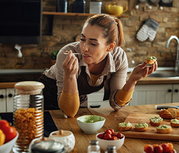 Mlada ženska za obiske pripravlja slasten zdrav prigrizek in uživa v majnih pregrehah.