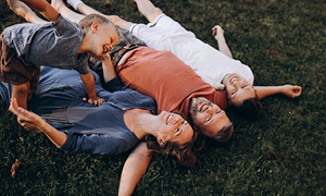 Družina leži v travi in uživa občutek varnosti, ki jim ga daje življenjsko zavarovanje obeh staršev.