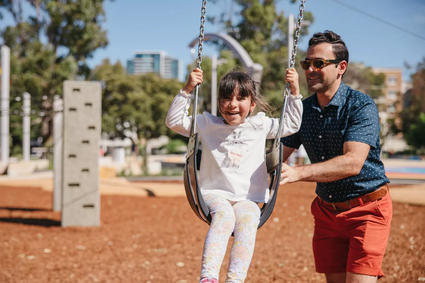 A child being pushed on a swing at the Wellington Square playground